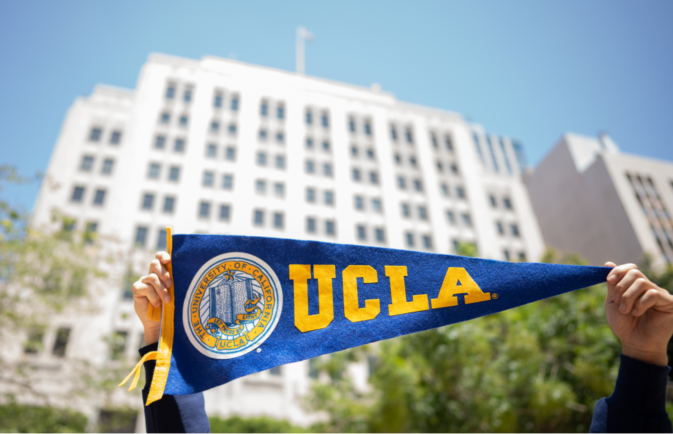 UCLA pennant held up in front of the historic Trust Building in downtown Los Angeles.